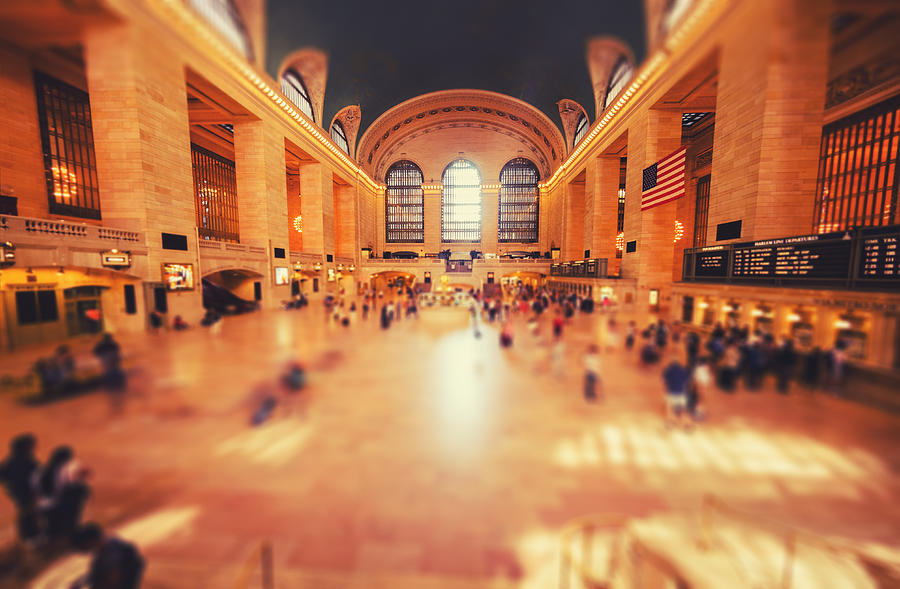 A dreamy tilt-shift photograph of Grand Central Terminal's main concourse filled with crowds of people, evoking the overwhelming but electric energy of a massive literary gathering where chance encounters and creative community collide